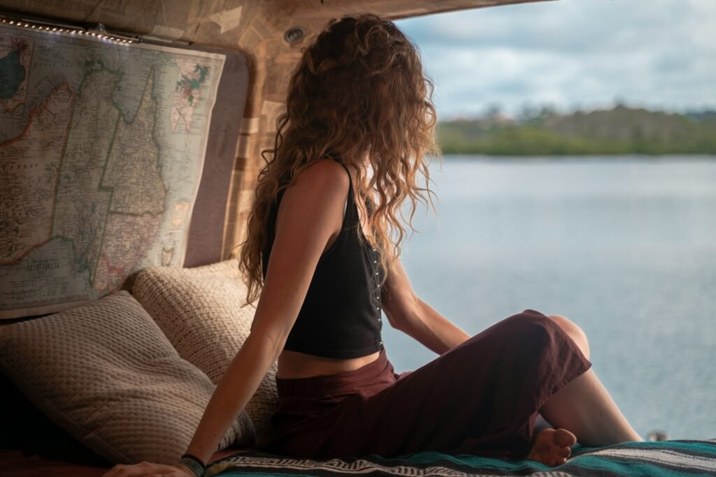 Woman wearing black spaghetti strap top sitting viewing body of water